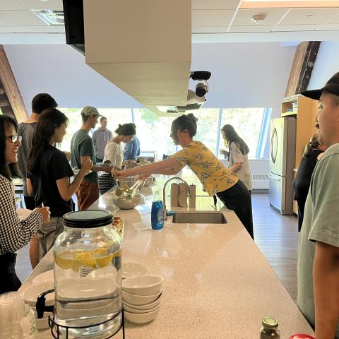 Students serve themselves lunch while talking in line.